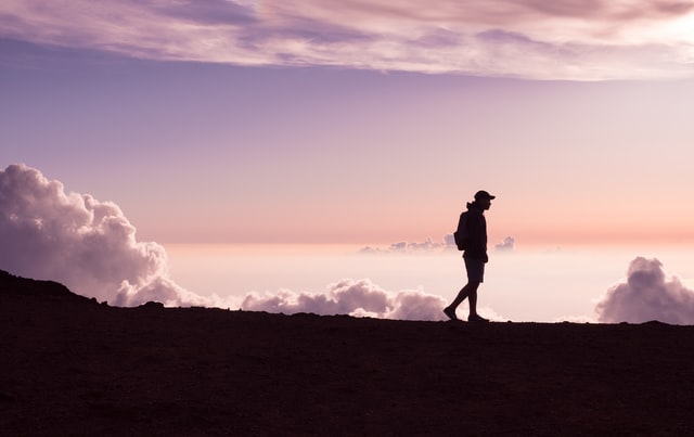 silhouette of man walking with clouds in the background