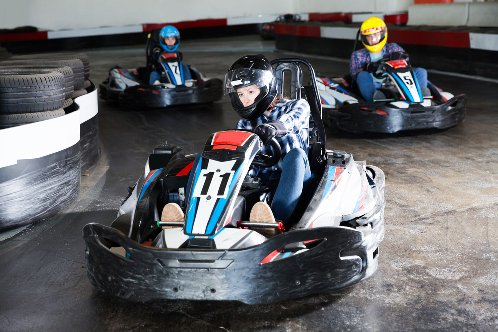 tres adolescentes montados en kartings haciendo un circuito