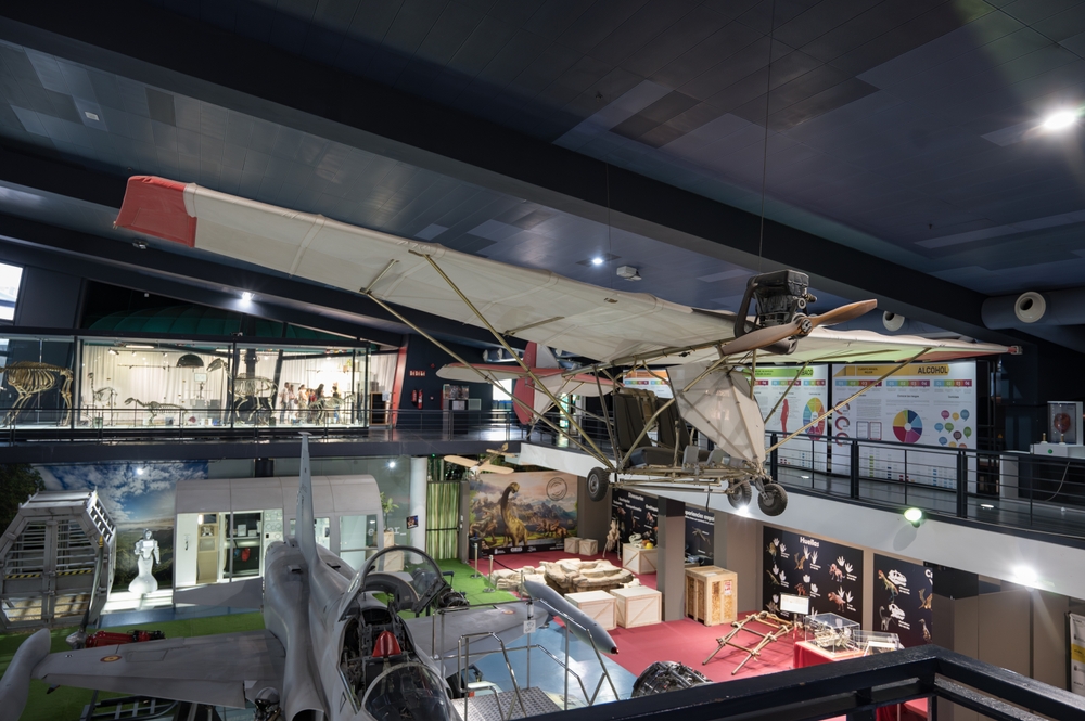 Interior del museo de ciencia y tecnología Elder de Gran Canaria con un avión de combate y un avión primitivo en el techo