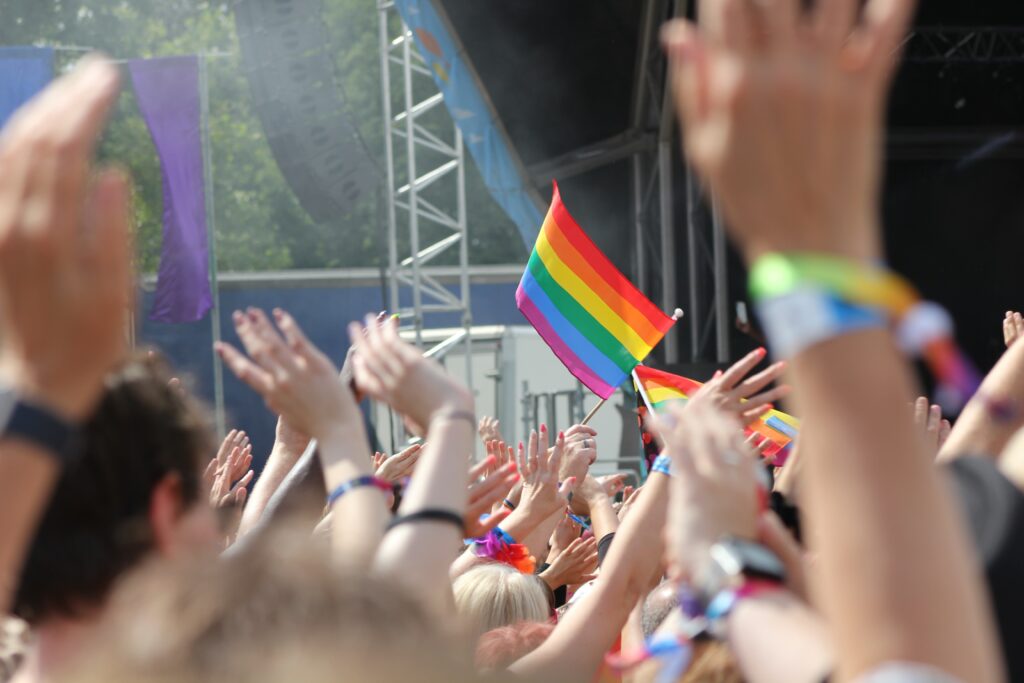people with their hands in the air and a rainbow flag on gay pride