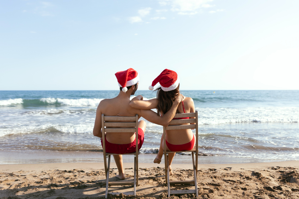 personas con gorro de papa noel en la playa
