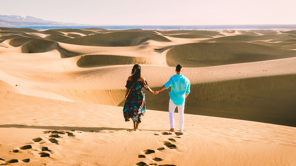 Pareja paseando al atardecer por la playa de Maspalomas