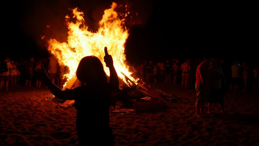 People gathered around fire at San Juan Night wearing different clothes
